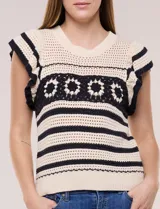 Buzo tejido en punto calado estilo crochet color beige con rayas horizontales negras y una franja central con motivos florales. Presenta cuello redondo, mangas cortas con volados y terminaciones en rib.