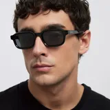 Lentes de sol con montura rectangular de diseño clásico y contemporáneo, con esquinas suavemente redondeadas. Presentan un acabado en color negro tanto en la montura como en los cristales.