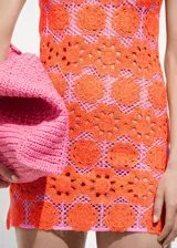 Vestido corto de crochet con diseño de flores color naranja sobre forro rosa, de tirantes anchos y escote cuadrado.