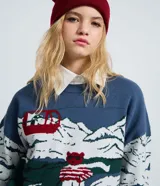 Suéter de punto jacquard de manga larga y cuello redondo con diseño invernal que incluye montañas, un teleférico rojo y un oso esquiando, con terminaciones caneladas en puños y ruedo.