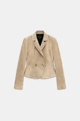 Blazer corto de cuero en color tostado, con cuello solapa, hombreras y manga larga. Presenta un diseño evasé en el bajo y un cierre frontal cruzado con dos botones.