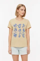 Remera de algodón color beige, de manga corta, cuello redondo y corte holgado. Presenta un estampado frontal en tonos azules con diseño de diversas frutas.