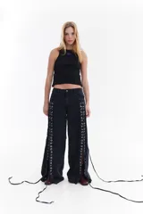 Jean wide leg de tiro medio y color negro gastado, con detalles de ojalillos metálicos a lo largo de los laterales delanteros y cordones de denim entrelazados.