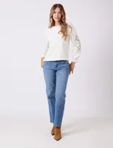 Buzo blanco de modal, corte clásico, con mangas largas abullonadas y apliques de crochet floral en los hombros y parte superior de las mangas.