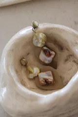 Par de aros colgantes con base dorada, cuentas de nácar irregulares y dijes cuadrados de nácar con detalles marrones.