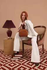 Bandolera de diseño compacto en color marrón claro, confeccionada en material símil cuero con textura granulada. Presenta un compartimento principal con cierre, un bolsillo frontal con cierre y correa regulable.