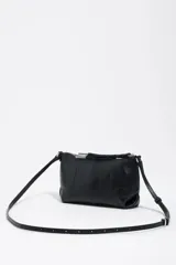 Bolso bandolera mini de piel vacuna color negro, con estructura blanda, asa regulable, cierre de cremallera y logo metálico de la marca.