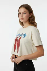 Remera crop top de algodón color crema con cuello redondo y mangas cortas. Presenta un estampado frontal con la frase 'spicy life everyday' y un diseño de ajíes rojos.