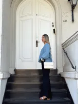 Camisa celeste de jean con cuello en V, mangas largas abullonadas con puños de encaje y cierre frontal con botones.