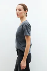 Remera gris oscuro de manga corta, con escote en V y aplicación de tachas plateadas en los hombros.
