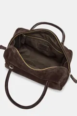 Bolso tipo bowling de piel vuelta, color marrón, con doble asa de mano y cierre de doble cremallera.