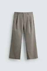 Pantalón relaxed fit color marrón con patrón de espiga, confeccionado en tejido con viscosa. Presenta pliegues frontales, bolsillos laterales y bolsillos traseros de vivo. Cierre frontal con cremallera y botón.