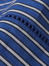 Camisa de manga larga a rayas verticales azules y blancas, con cuello inglés y corte amplio. Presenta detalles distintivos de la marca Tommy Hilfiger y logo bordado en el puño.