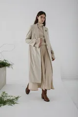 Tapado largo de paño en color beige, con solapas clásicas, cierre frontal de dos botones y corte recto estructurado.