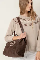 Bolso tipo tote bag de gamuza azul con asas de cuero marrón y bolsillo externo con logo bordado.