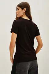 Remera negra de viscosa con cuello redondo y manga corta, presenta una estampa central de estrella grande decorada con lentejuelas brillantes.