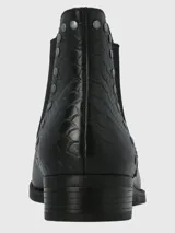 Bota corta de cuero negro con diseño de paneles laterales con textura tipo reptil y detalle de tachas metálicas plateadas a lo largo del empeine. Cuenta con un tacón bajo y suela de caucho.