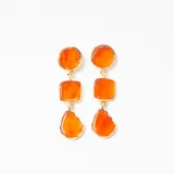 Caravanas colgantes compuestas por tres piezas de resina en tono naranja con efecto marmolado, engarzadas en metal dorado. El diseño presenta formas geométricas variadas: un círculo, un cuadrado y una forma irregular tipo gota.