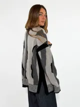 Sweater de tejido de punto con diseño abstracto de rayas irregulares en tonos azul y marrón. Presenta cuello redondo, mangas largas con caída de hombro y puños y ruedo acanalados.