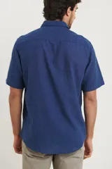 Camisa sport de manga corta, confeccionada en una mezcla de lino y algodón. Presenta cuello clásico, cierre frontal con botones de coco y un bolsillo aplicado en el pecho.