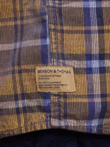 Camisa de pana color azul marino, con mangas largas, cuello clásico y dos bolsillos frontales con solapa y botón.