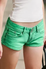 Shorts de jean tiro bajo color verde, con diseño clásico de cinco bolsillos, trabillas para cinto y cierre frontal con cremallera y doble botón metálico.
