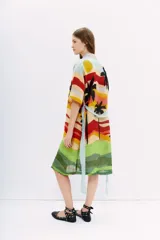 Kimono largo de lino con estampado vibrante que simula un paisaje de atardecer con palmeras, en franjas horizontales de colores cálidos y verdes. Posee mangas amplias y lazo para ajustar en la cintura.