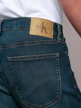 Jeans de corte recto y talle medio, confeccionados en denim elástico con diseño clásico de cinco bolsillos, cierre de cremallera y botón.