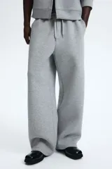 Pantalón tipo jogger de corte relajado con efecto neopreno, cintura elástica con cordón ajustable, bolsillos laterales al bies y bolsillo trasero de parche.
