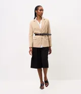 Blazer sastre color beige, de corte estructurado y calce al cuerpo, con solapa clásica, bolsillos con solapa en los laterales, bolsillo superior y cierre frontal de un botón.