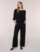 Pantalón pull-on de color beige con caída fluida, cintura elastizada fruncida, bolsillos laterales funcionales y pierna amplia de corte wide leg.