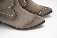 Bota tejana de caña baja color tostado, confeccionada en cuero, con taco bajo y detalles de tachas metálicas en las costuras y la puntera.