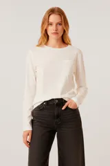 Remera de manga larga confeccionada en algodón de color blanco, con cuello redondo y un bolsillo aplicado en el pecho. Presenta un diseño de calce al cuerpo.