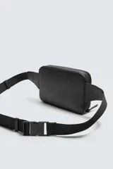 Riñonera negra con textura grabada, compartimento principal con cierre de cremallera y bolsillo frontal plano. Incluye asa ajustable con hebilla metálica de liberación rápida.