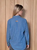 Camisa de jean de corte clásico, con cuello camisero, cierre frontal con botones y mangas largas con puños abotonados.