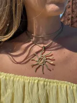 Collar con cordón ajustable color beige y dije de sol plateado.