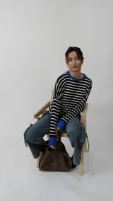 Remera de manga larga con diseño a rayas horizontales en blanco y negro, destacada por su cuello redondo y puños en color azul vibrante. Presenta un corte relajado y cómodo.