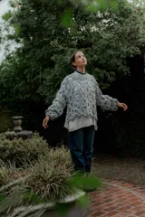 Buzo de tejido calado con diseño de red, de corte holgado y mangas largas abullonadas. Presenta un estilo artesanal con textura abierta.