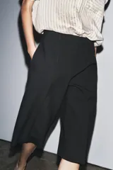 Bermuda larga color marrón oscuro, de tiro medio con cintura con trabillas. Presenta bolsillos laterales ocultos en la costura y detalle de raya planchada. Cierre frontal con cremallera, botón y ganchos metálicos.