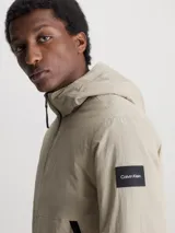 Campera beige con capucha, cierre frontal con cremallera, bolsillos laterales con cremallera y logo de Calvin Klein en la manga.