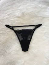 Conjunto de lencería compuesto por bralette triangular, tanga y portaligas, confeccionado íntegramente en encaje negro con detalles de breteles regulables.