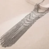 Collar de estilo pechera compuesto por múltiples hileras de cadenas finas doradas y eslabones tubulares, creando un diseño en cascada con gran caída.