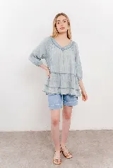 Blusa celeste de gasa con escote en V, mangas tres cuartos y diseño en capas con volados.