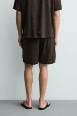 Bermuda de corte regular confeccionada en tejido fluido con textura jacquard geométrica. Presenta cintura elástica con cordón ajustable, bolsillos laterales y bolsillos traseros de vivo.