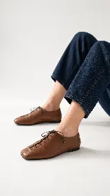 Zapato de cuero color off white, estilo acordonado con punta cuadrada y finos cordones tono sobre tono.