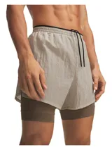 Short de running Under Armour de doble capa, color beige claro en la capa exterior y marrón oscuro en la calza interior ajustada.