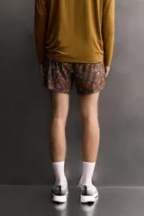 Shorts deportivos de Zara Athleticz confeccionados en tejido técnico ligero con estampado camuflado en tonos marrones y naranjas. Poseen cintura elástica ajustable, forro interior y aberturas en el bajo.