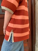 Remerón de algodón a rayas horizontales color naranja y salmón, con cuello tipo polo y mangas cortas.