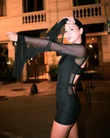 Vestido corto negro con escote en V cruzado, mangas largas amplias y detalle de lazo ajustable en la cintura.