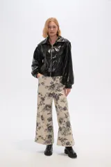 Chaqueta corta de cuero sintético negro con cuello camisero, cierre frontal con cremallera, bolsillos laterales y mangas largas abullonadas.